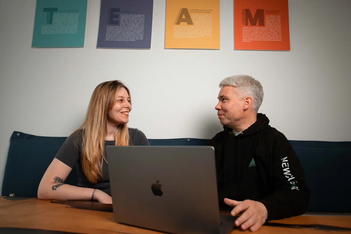 Zwei newcubator Teammitglieder sprechen direkt an einem Laptop über ein Projekt.