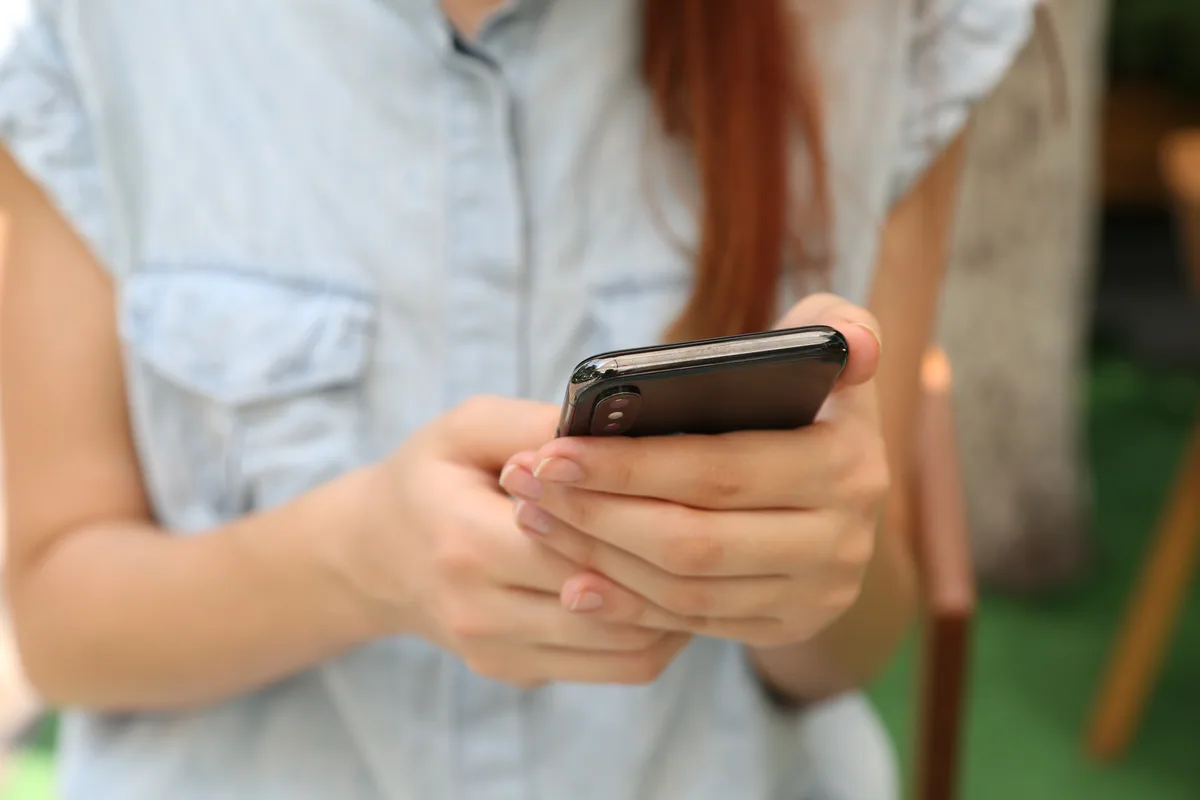 Person bedient ein Smartphone mit beiden Händen.