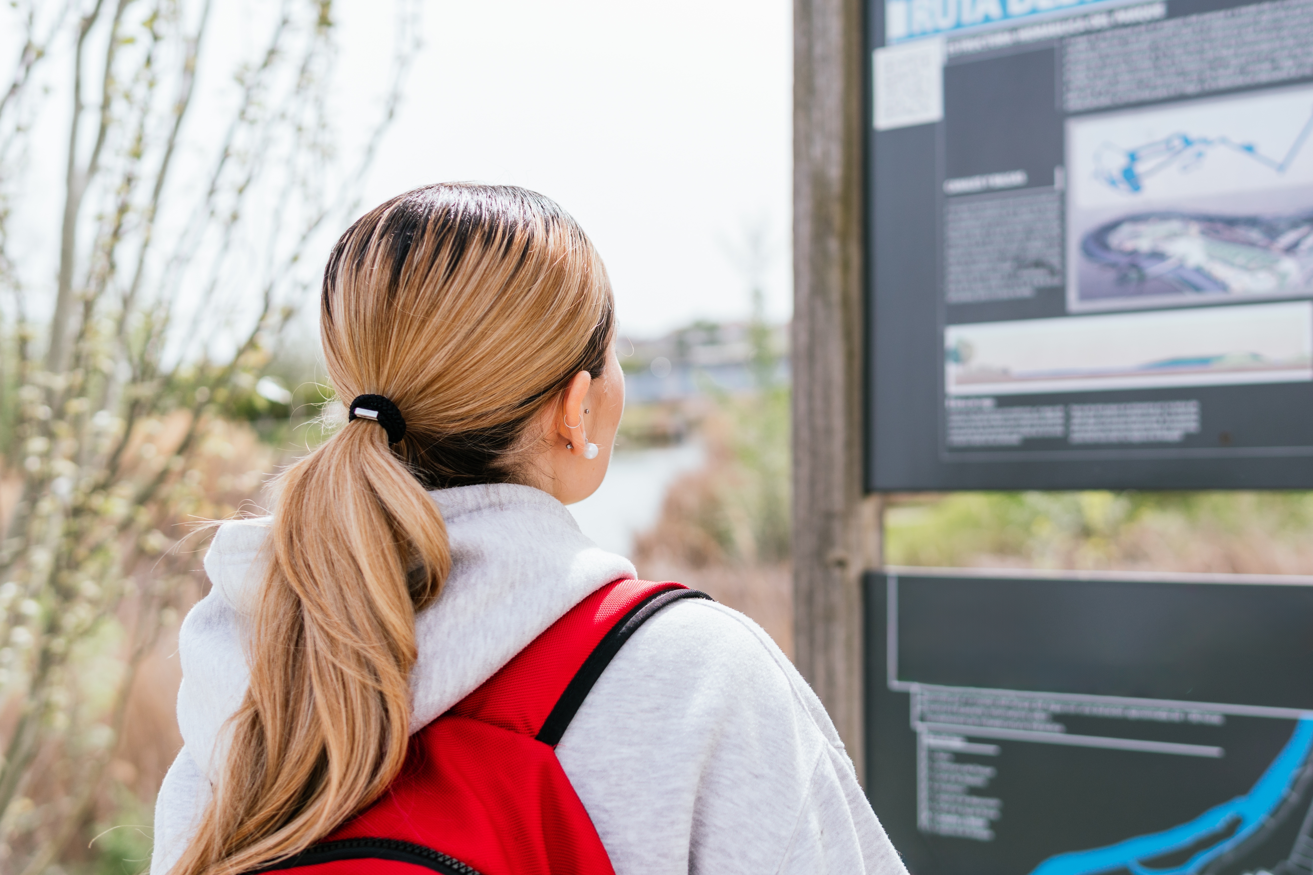Besucherin liest eine Informationstafel an einem touristischen Ort