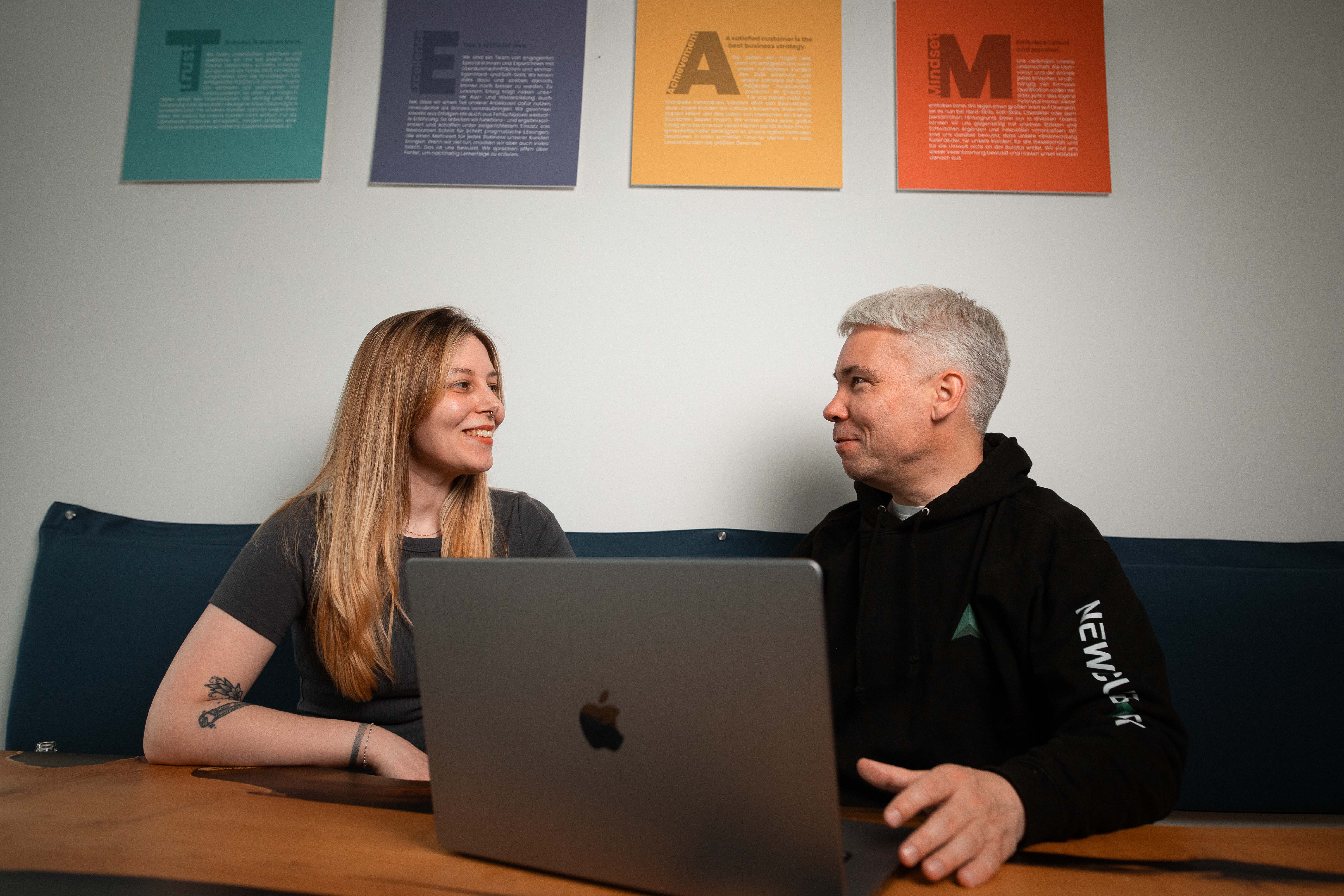 Zwei newcubator Teammitglieder besprechen ein Softwareprojekt direkt am Laptop.